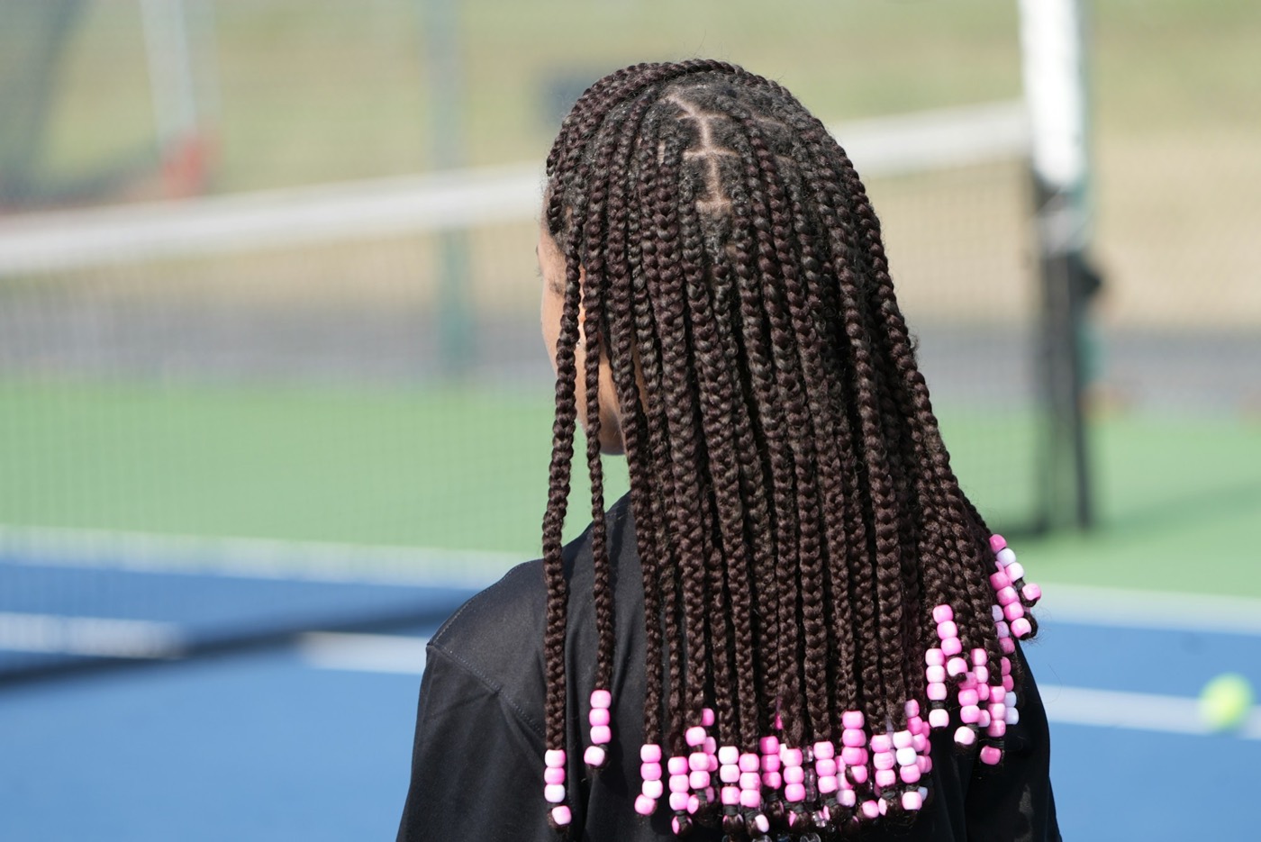 Long box braids with pink beads at the ends, seen from behind