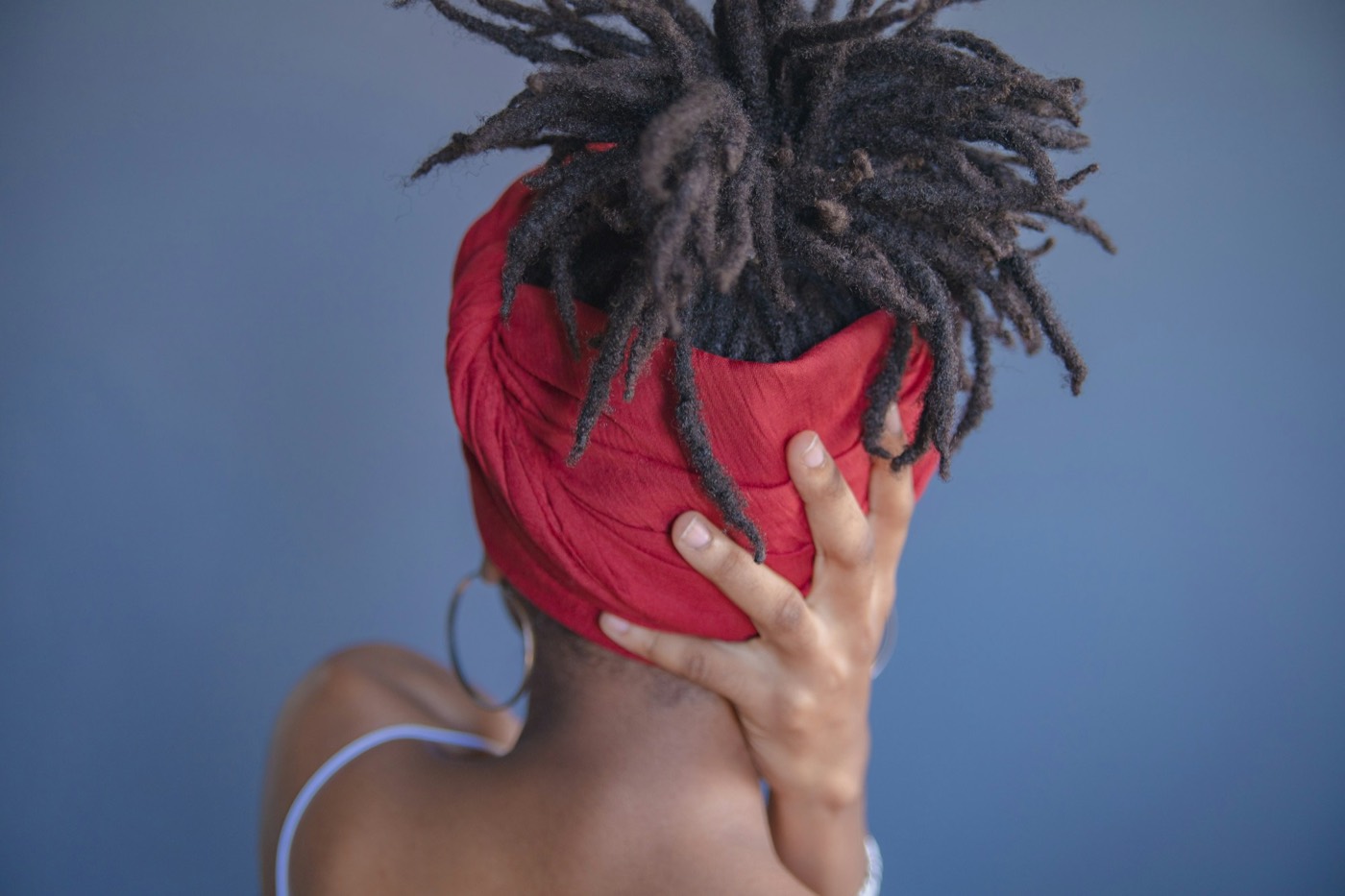Locs gathered up in a red head wrap, seen from behind