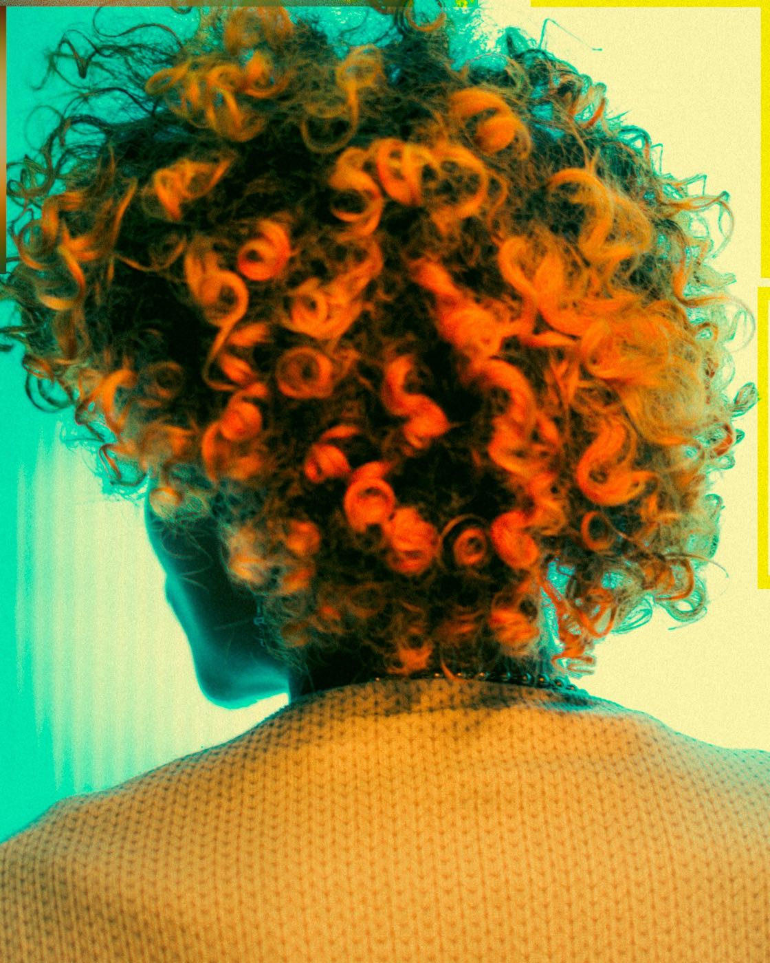 Short natural curls colored bright orange, seen from behind