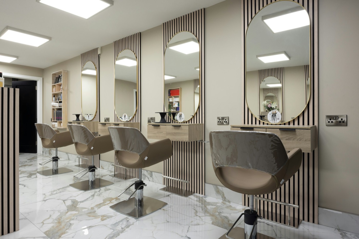 Empty salon chairs facing tall arched mirrors