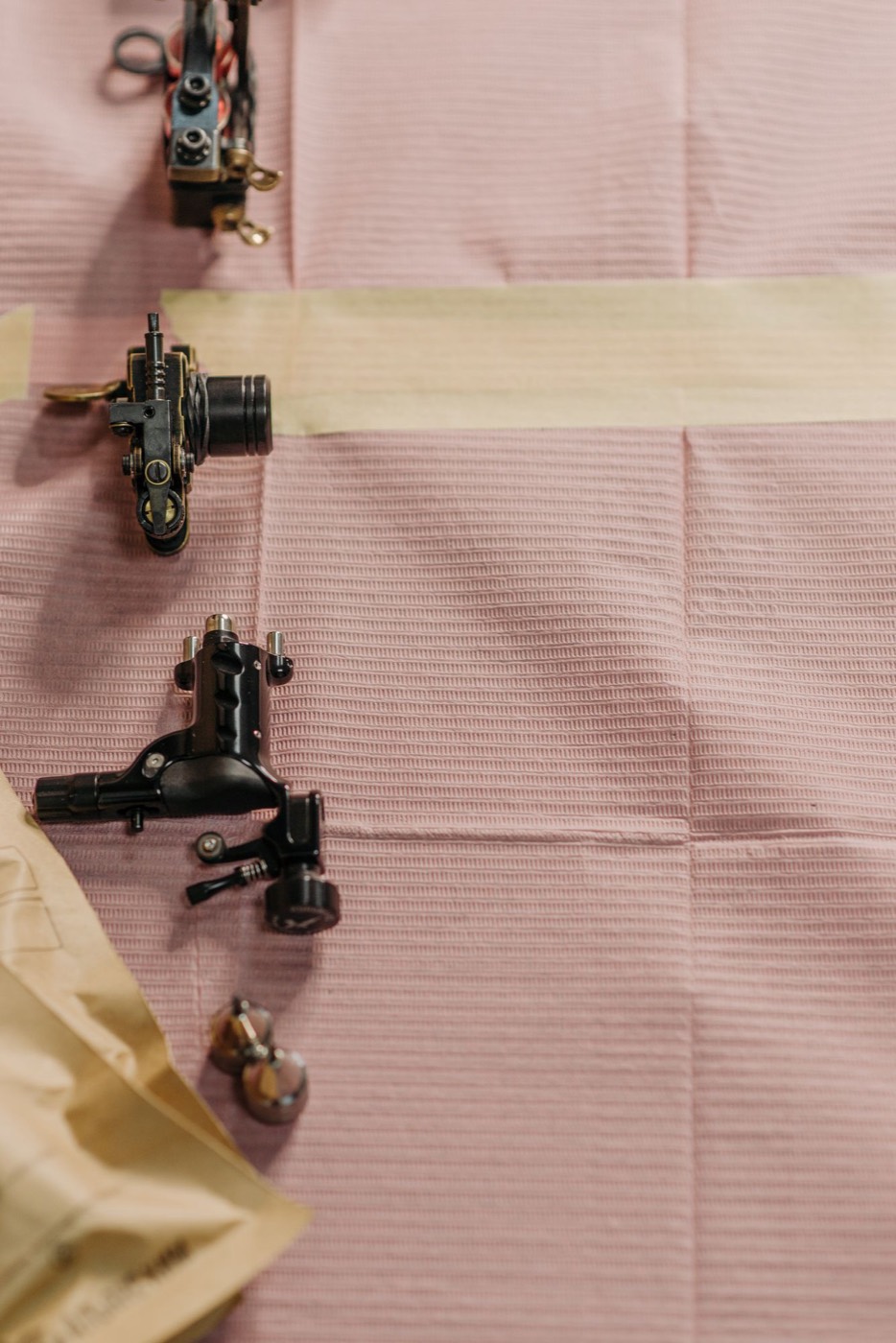 Tattoo machines laid out on a covered work table.