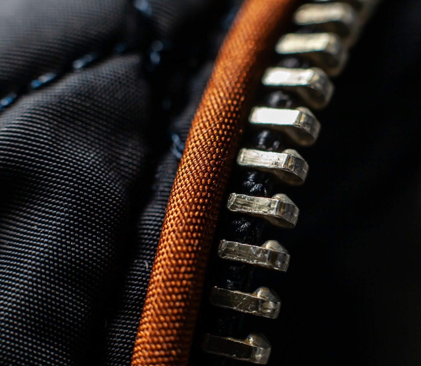 Metal zipper teeth up close on a dark quilted jacket
