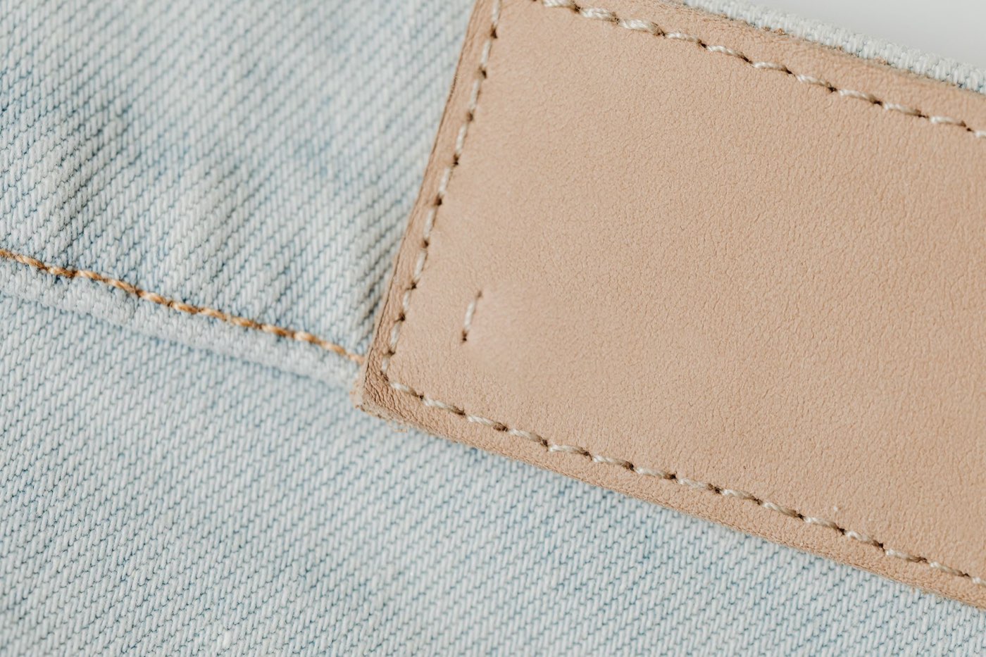 A plain leather patch stitched onto faded denim