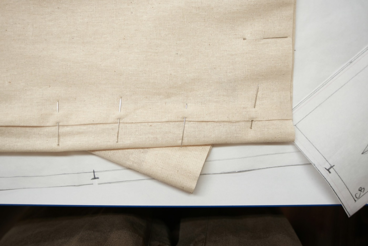 Pins holding a folded hem in place on a paper pattern