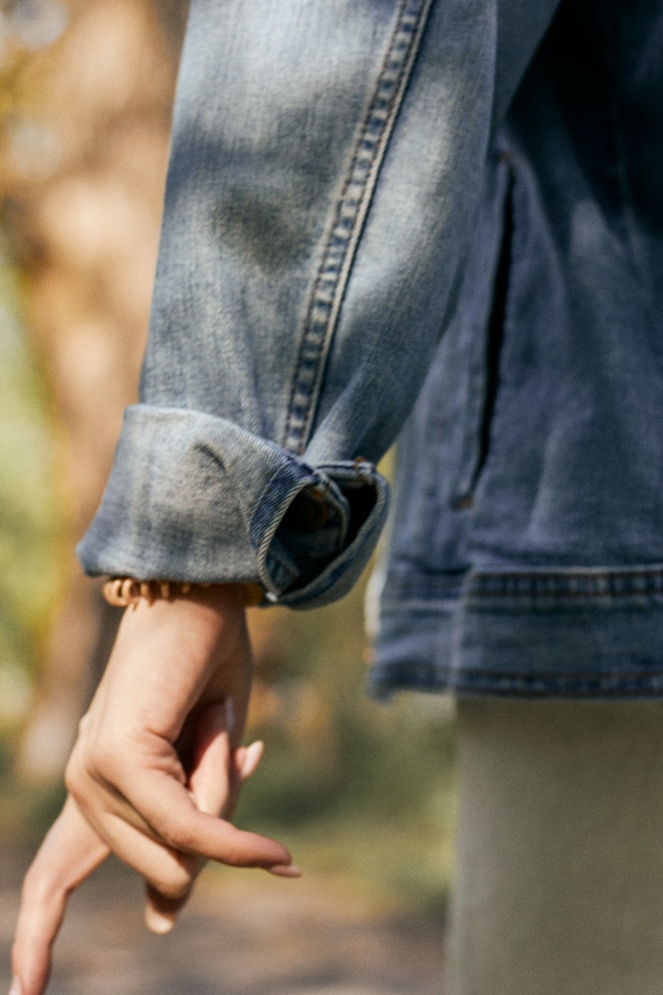 The rolled cuff of a worn denim jacket