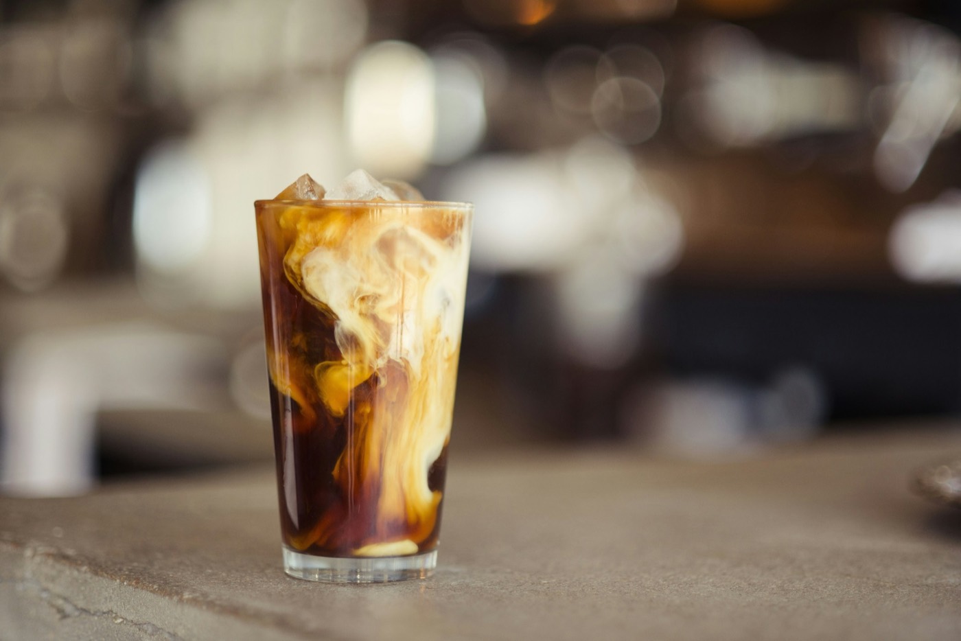 An iced latte in a tall glass on a cafe table