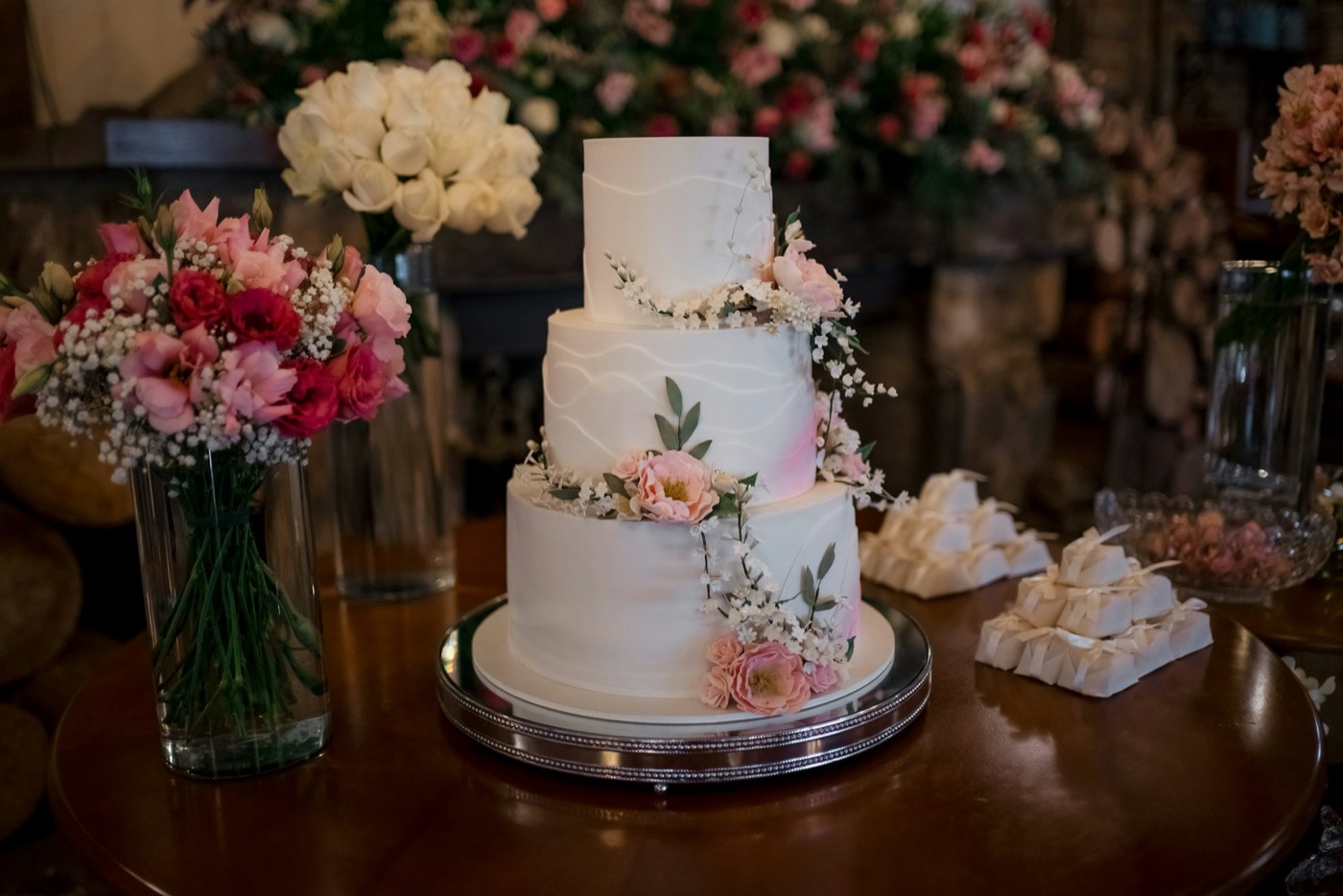 Three-tier white cake decorated with pink flowers on a cake stand