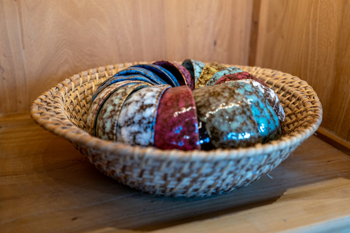 Glazed bowls stacked on edge in a round wicker basket