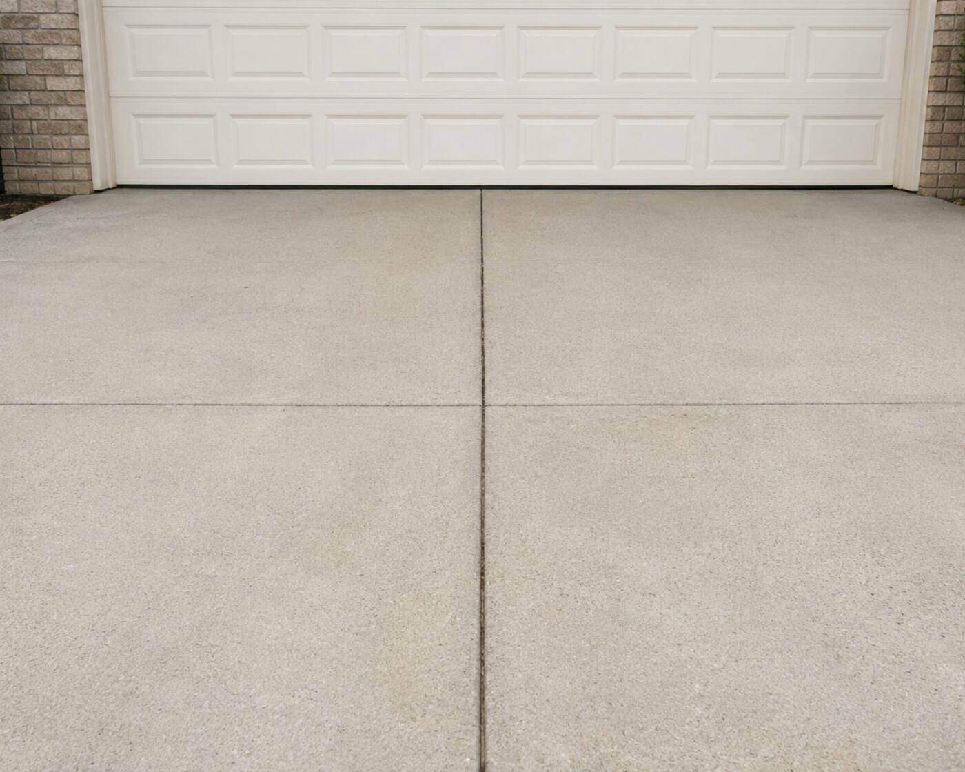 A clean concrete driveway in front of a white garage door