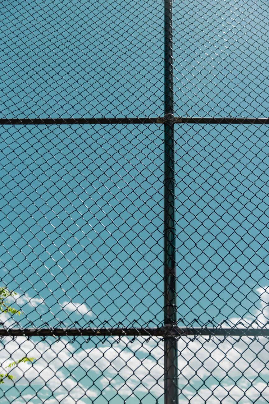 A black chain link fence against a blue sky