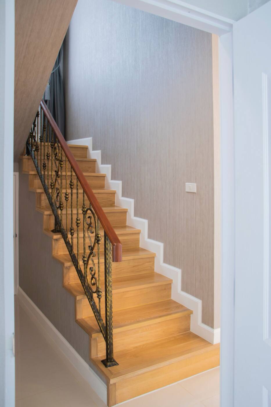 Wood stairs with white risers, a black iron railing and a wood handrail