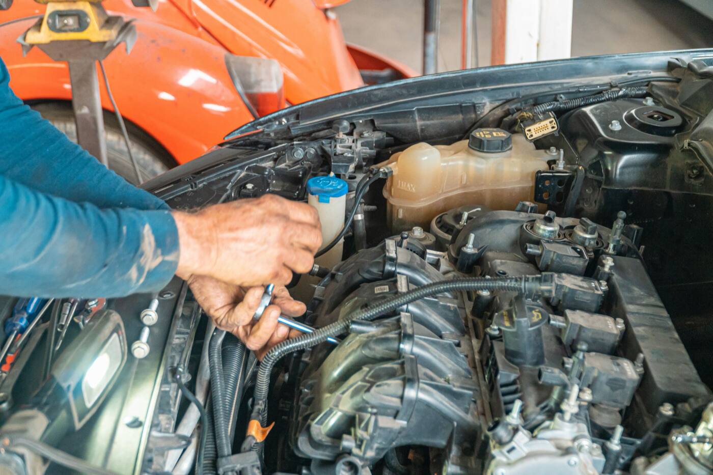 A mechanic's hands working in a car's engine bay