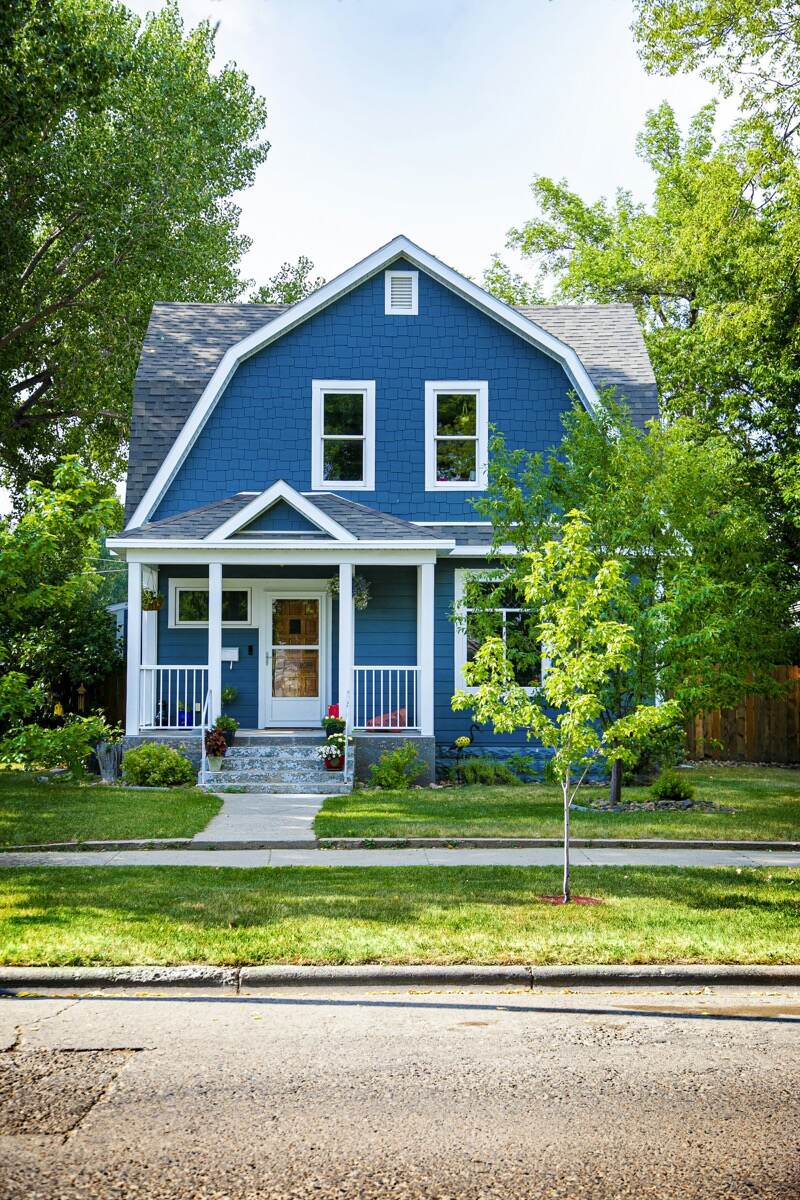 A small house with blue shake siding, white trim and a front porch